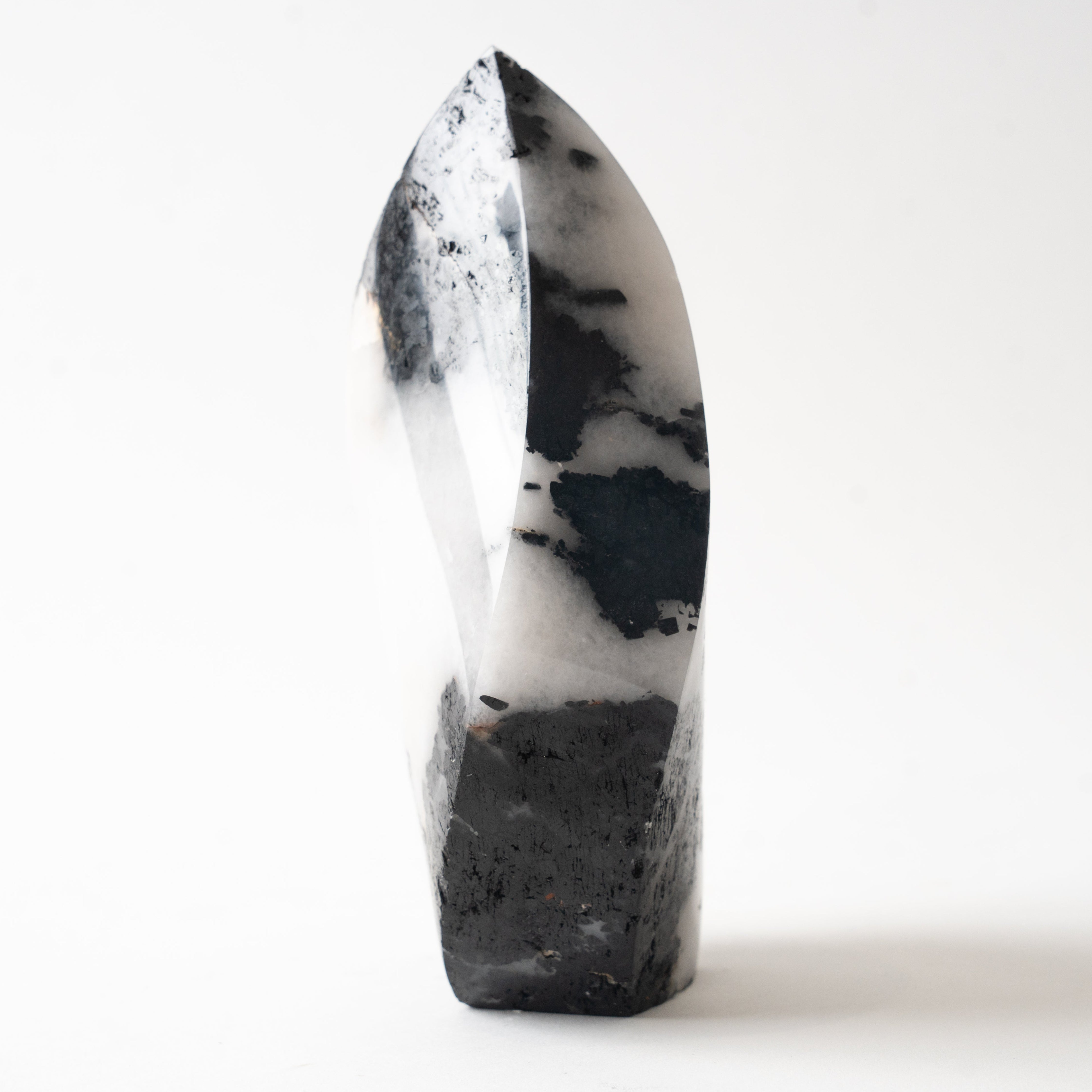 A faceted crystal tower featuring anatural black tourmaline and white quartz, standing upright on a clean white background.