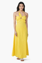 Woman wearing a yellow halter neck dress on a white background