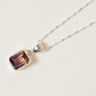Necklace with a purple Ametrine  gemstone pendant on a light gray background