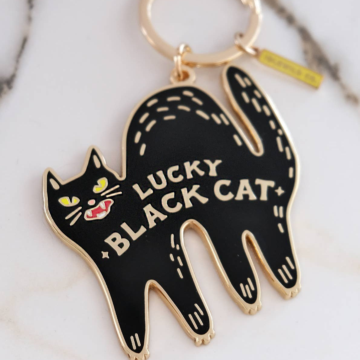 Black cat-shaped keychain with 'Lucky Black Cat' text on a marble surface