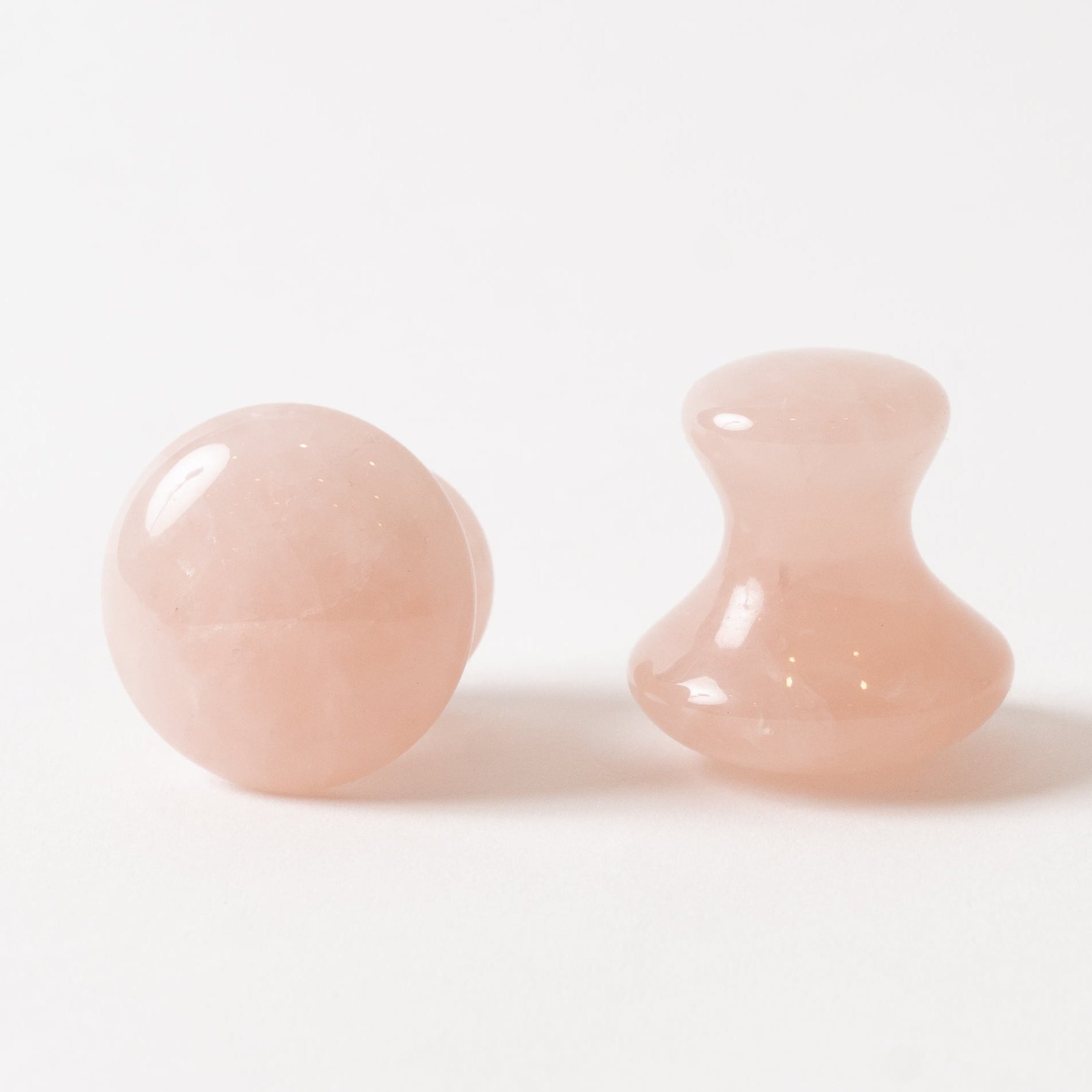 Two pink rose quartz massagers on a white background