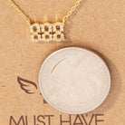 Gold necklace with a diamond-encrusted pendant on a coin and cardboard background