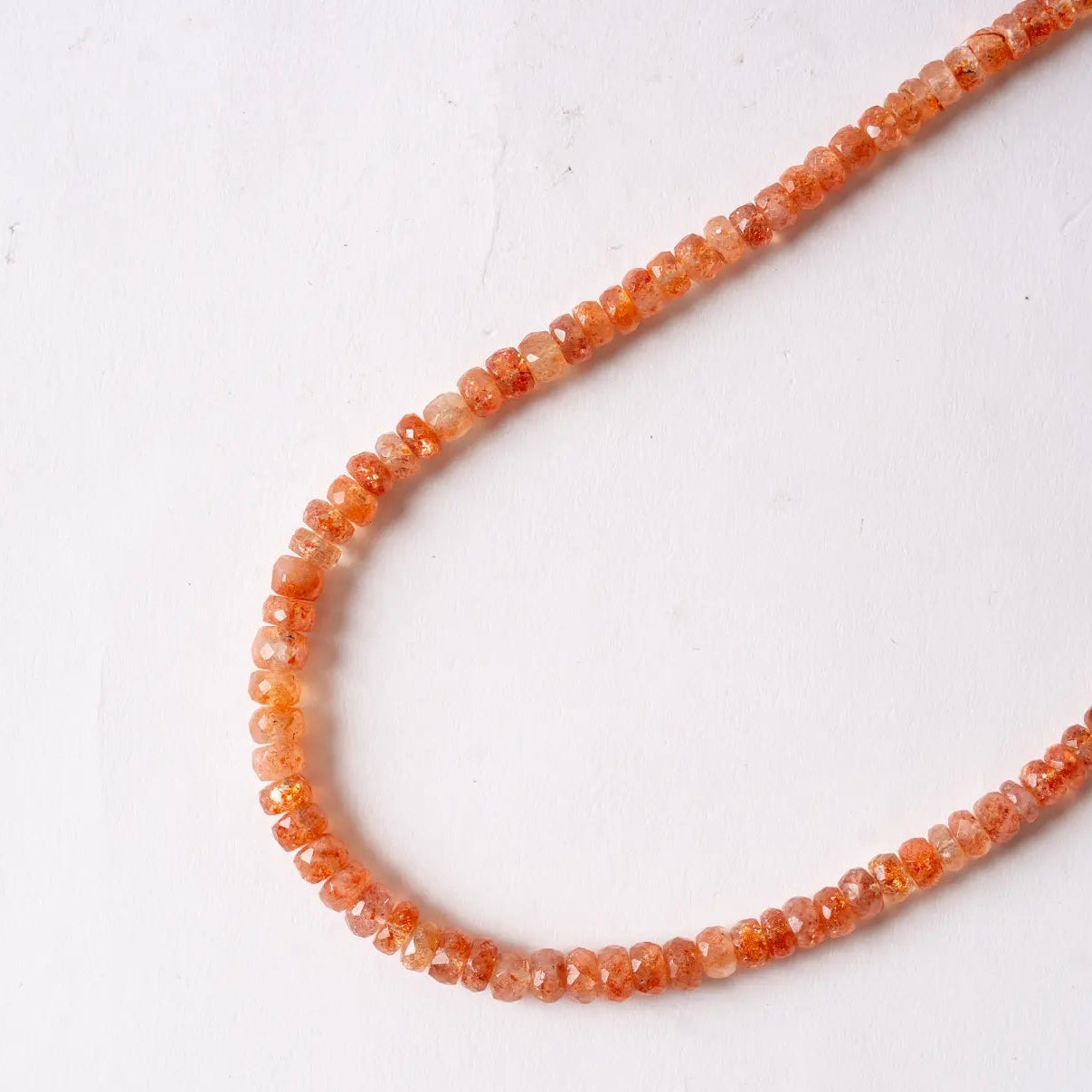 Necklace with orange sunstone beads on a white background