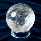 Bigger Clear crystal sphere on a dark blue fabric background