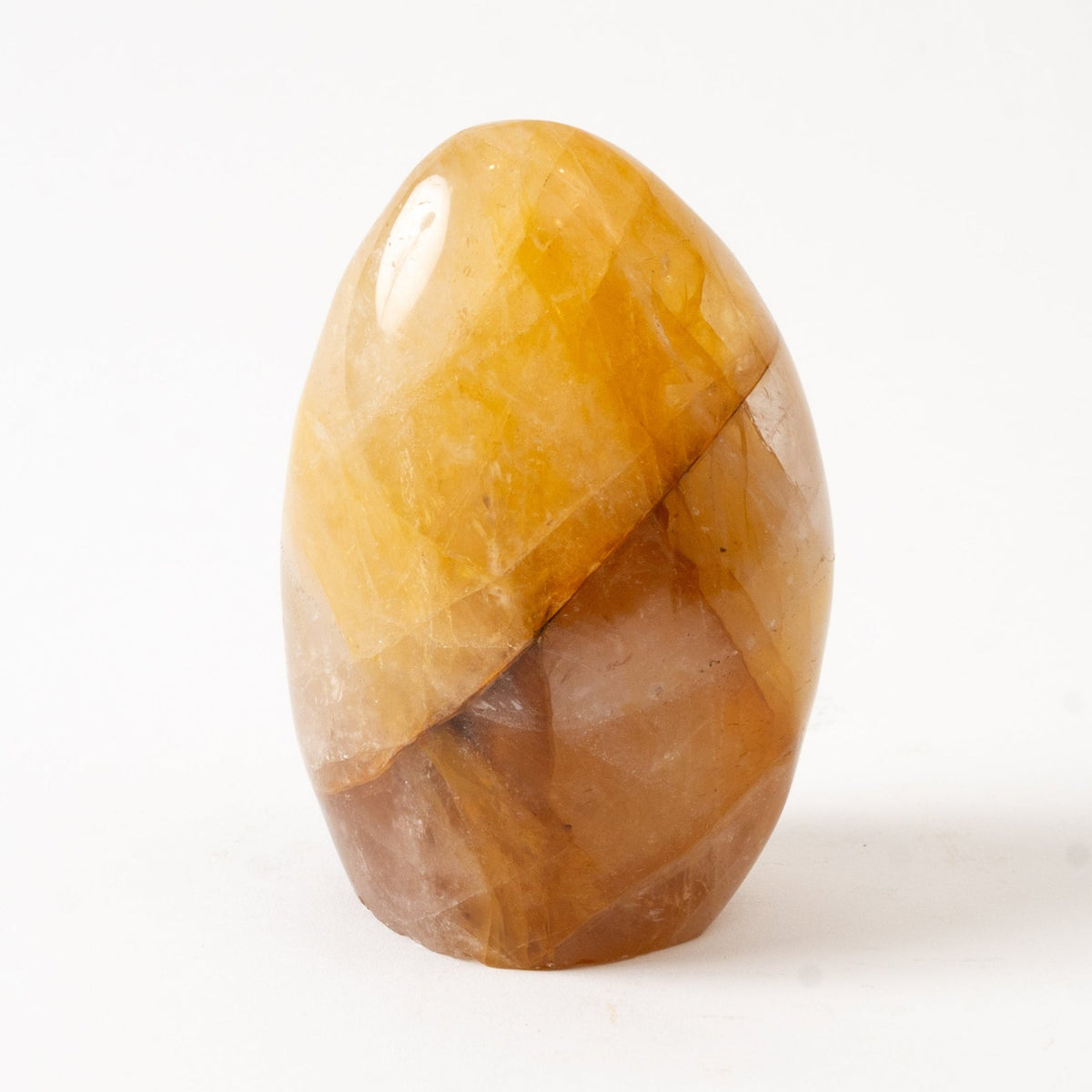 Polished amber-colored Golden Healer stone on a white background