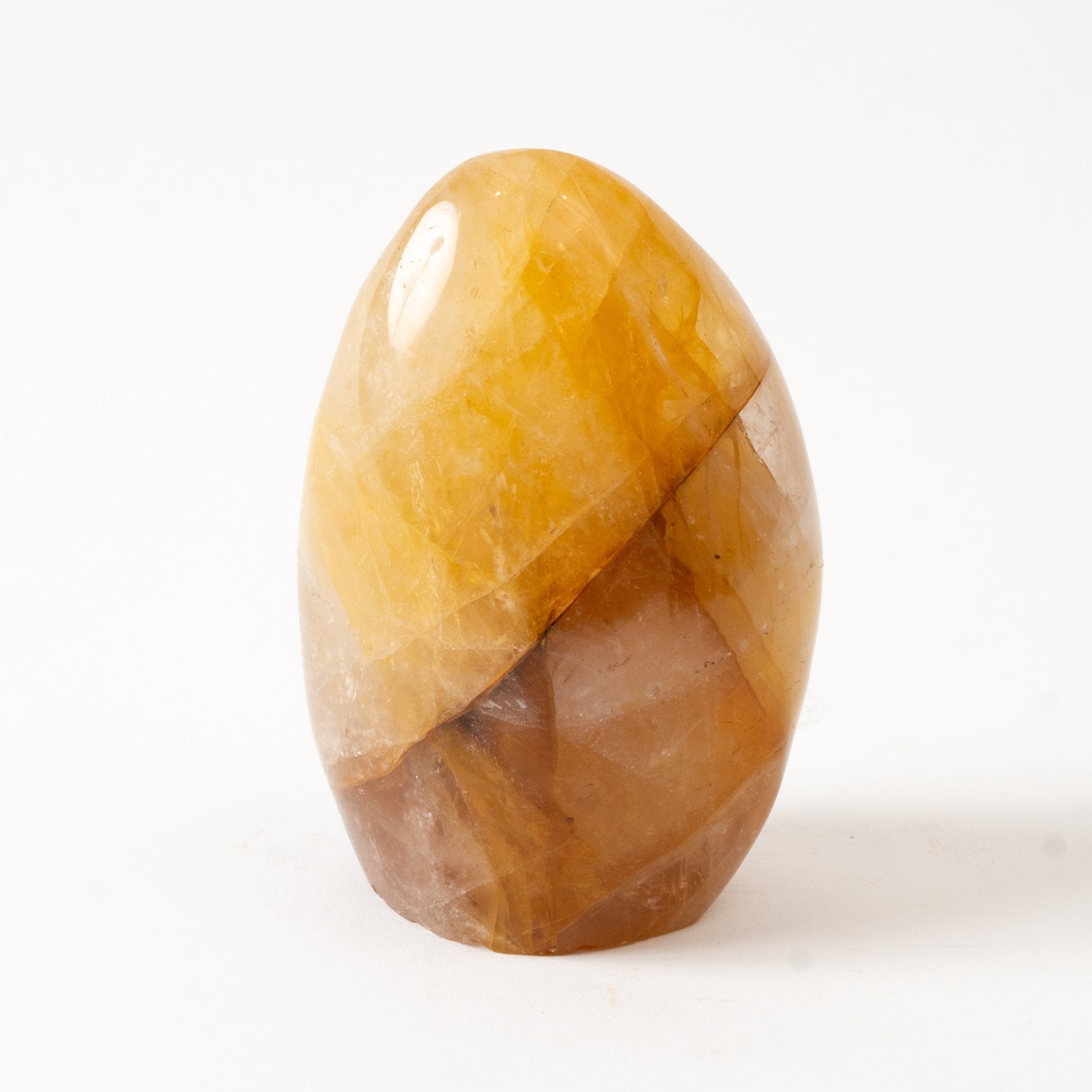 Polished amber-colored Golden Healer stone on a white background