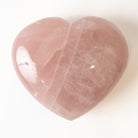 Heart-shaped pink rose quartz stone on a white background