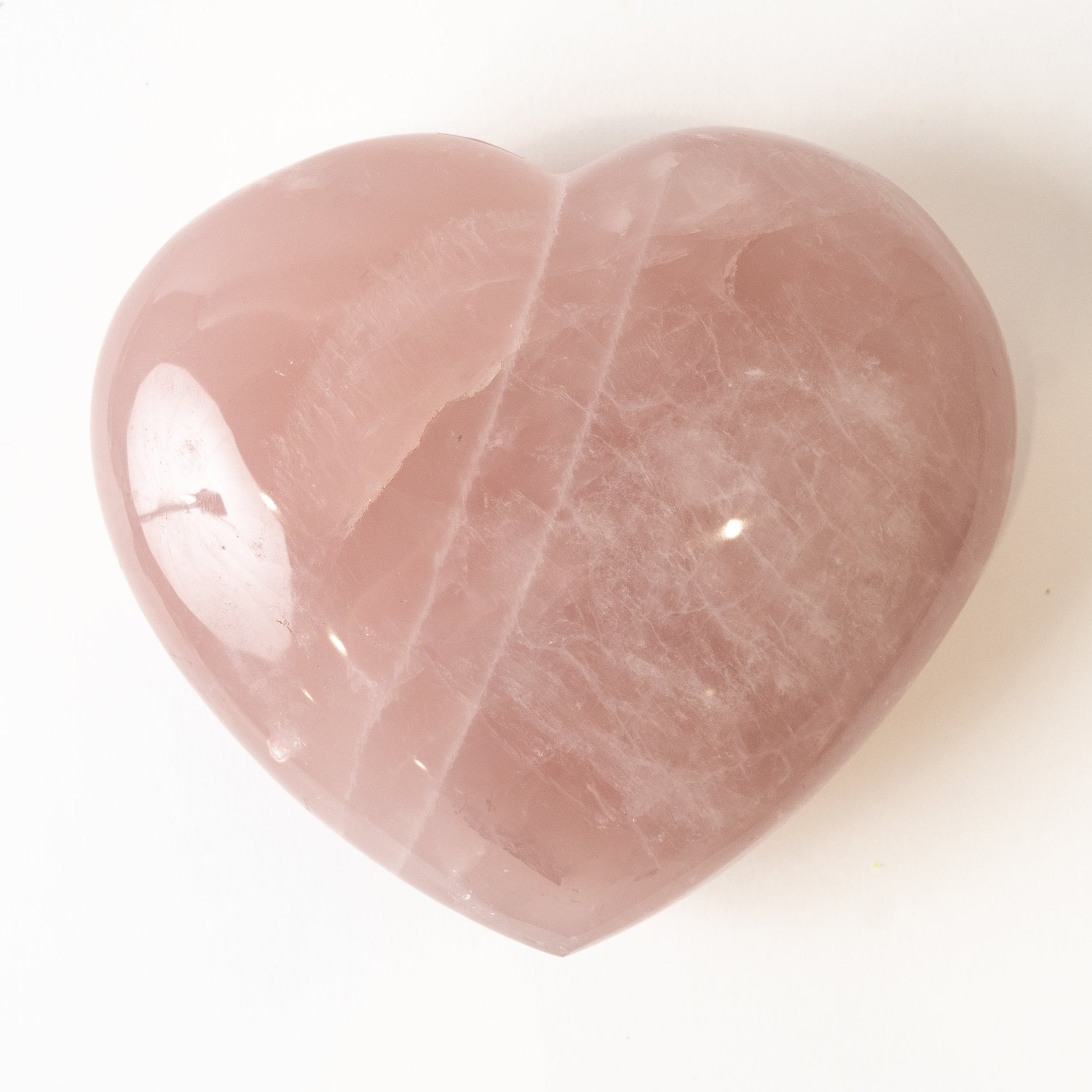 Heart-shaped pink rose quartz stone on a white background