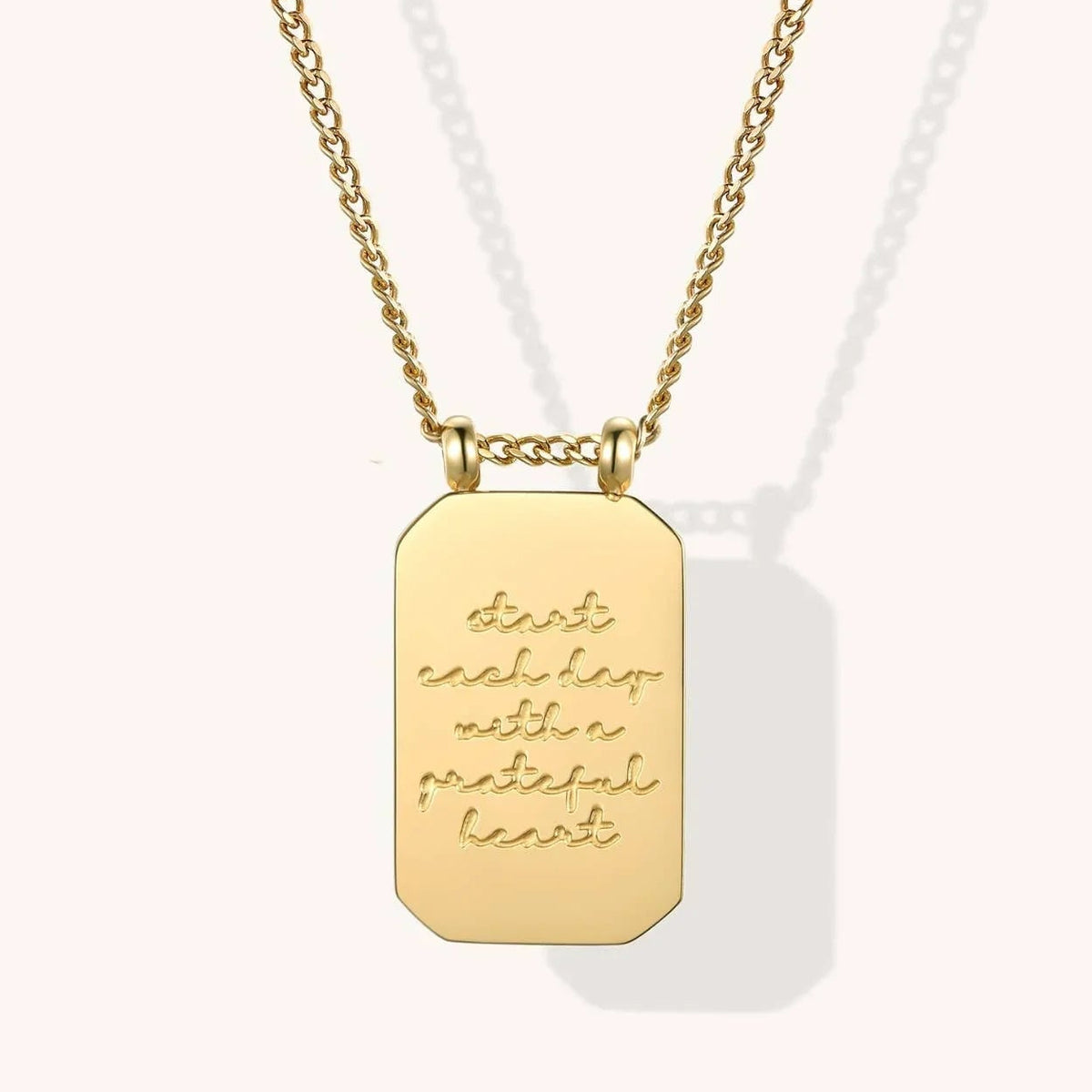 Gold necklace with a rectangular pendant on a white background
