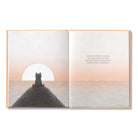 Open book with a silhouette of a person sitting on a mountain at sunset.
