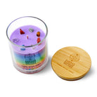 Candle with colorful stones and a wooden lid on a white background