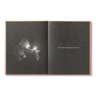 Open book with a bear illustration holding a light bulb on one page and text on the other, on a white background.