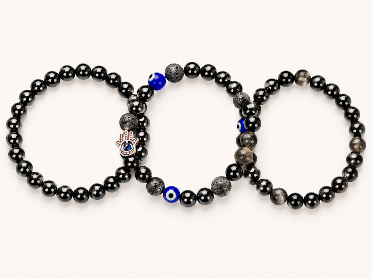 Three black beaded bracelets with blue evil eye beads on a white background
