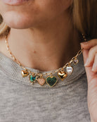 gold and green charm necklace on someone