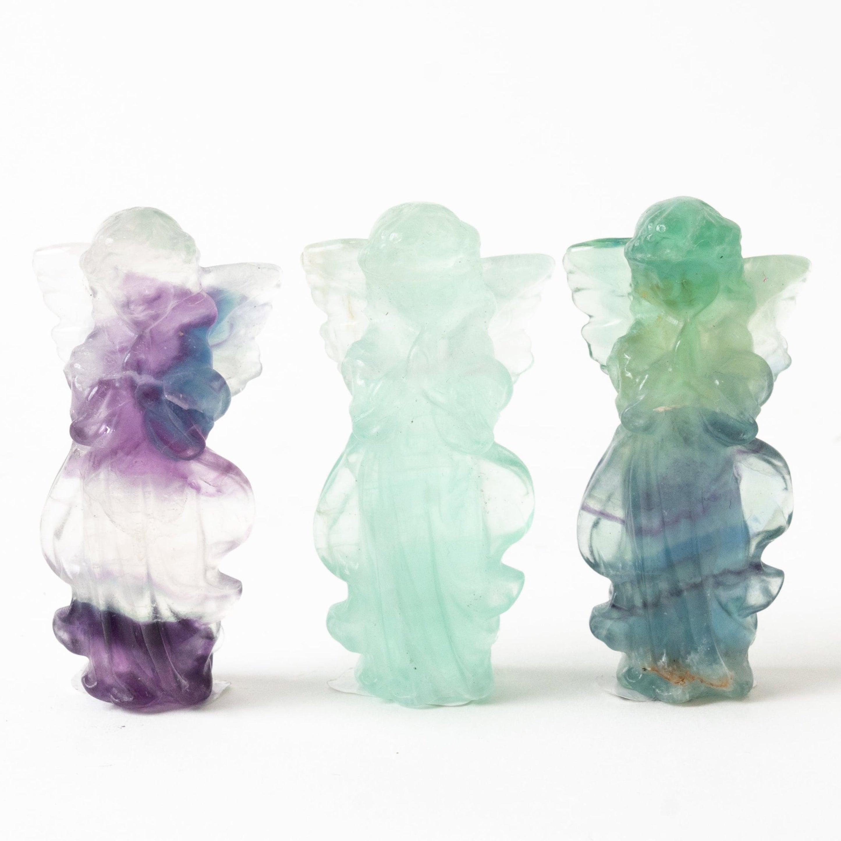 Three multicolored fluorite rcystal figurines on a white background