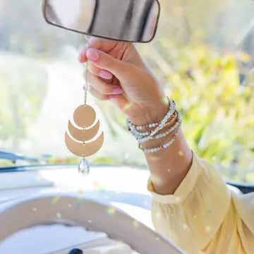 Hand holding a car air freshener with blurred outdoor background