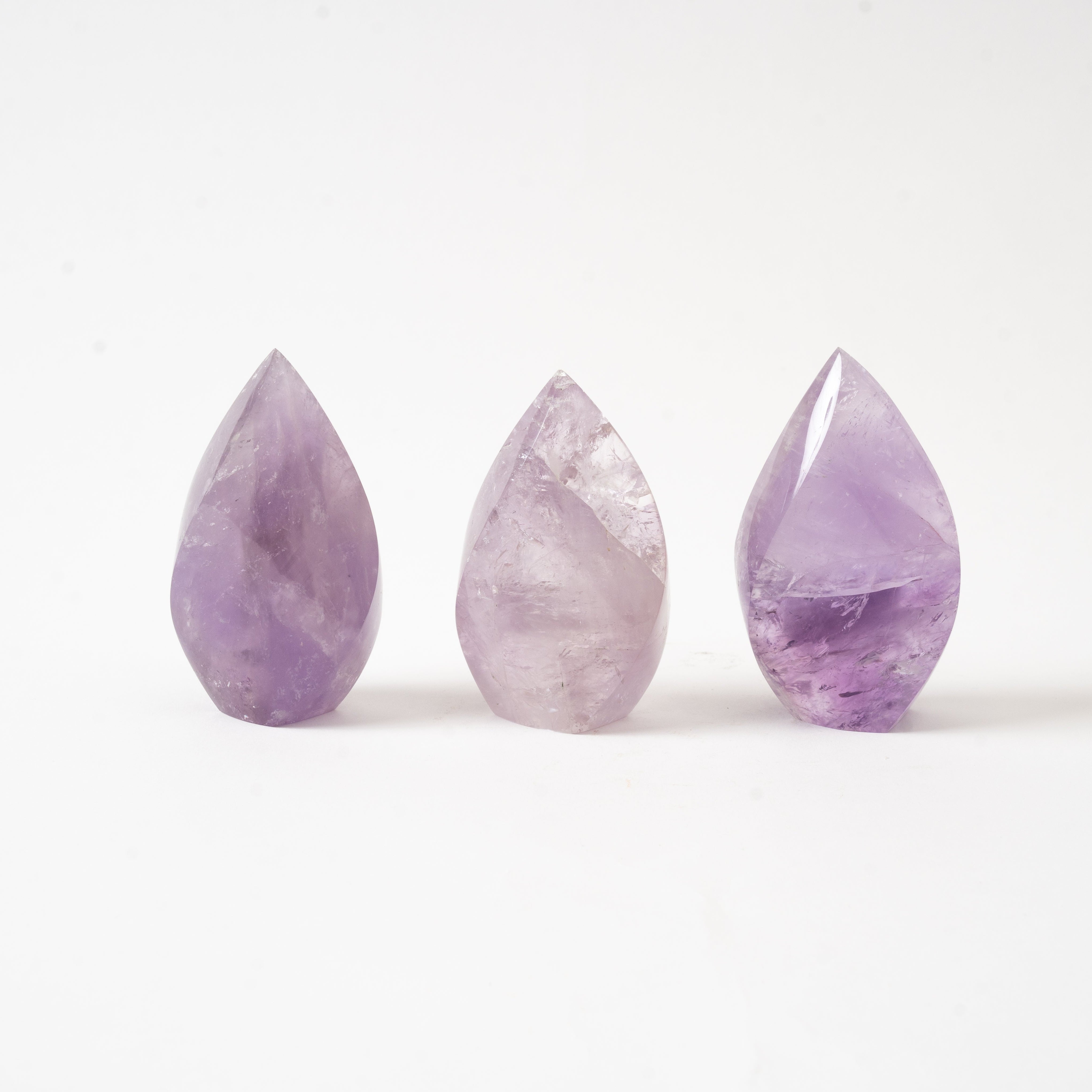 Three flame shaped Amethyst crystals on a white background