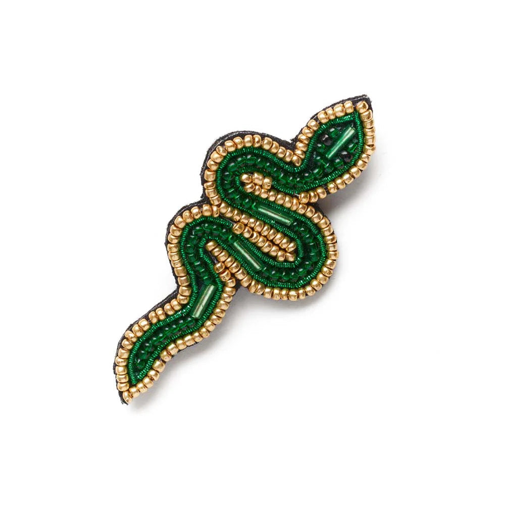 Decorative brooch with green and gold design on a white background