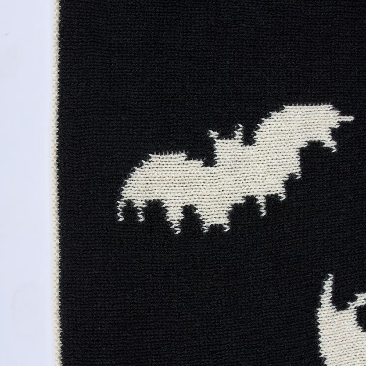 Black fabric with white knit pattern of a dog and cat on a light purple background
