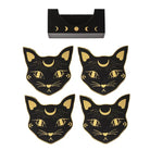 Four black cat-shaped coasters with gold celestial details are arranged below a matching black rectangular tray featuring moon phases, all on a plain white background.