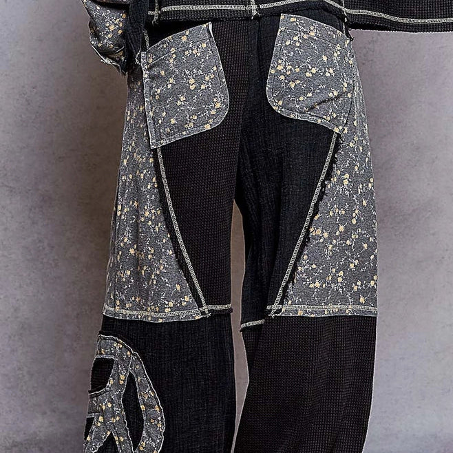 Person wearing a black outfit with decorative和平符号(pacifist symbol) on a patterned rug.
