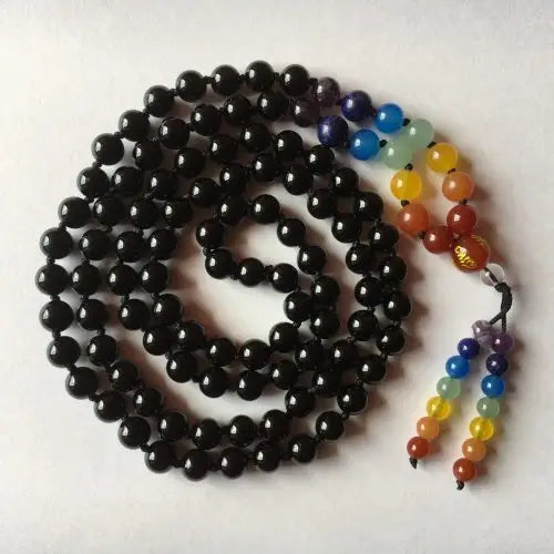 Black onyx beaded chakra mala necklace with a multicolored pendant on a white background