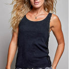 black lace and knit sleeveless tank top with textured, frayed edges and lace trim along the sides, paired with gray patterned pants, against a solid gray studio background.
