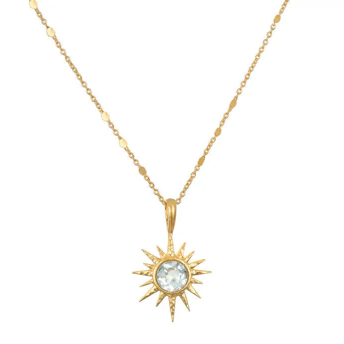Gold sun-shaped pendant necklace with a central gemstone on a white background