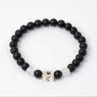 Black beaded Cancer Sun Sign bracelet with a silver cube charm on a white background