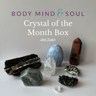 Crystal of the Month Box with various crystals on a white surface and gray background.