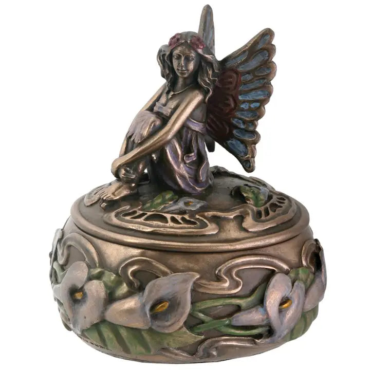 Decorative figurine of a fairy sitting on a lid with floral designs.