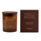 An amber glass jar candle with a wooden lid sits next to its matching dark brown packaging box. Both pieces feature the text 'WELL BEING' and 'RELAX & SLEEP' by Cerria Mollá.