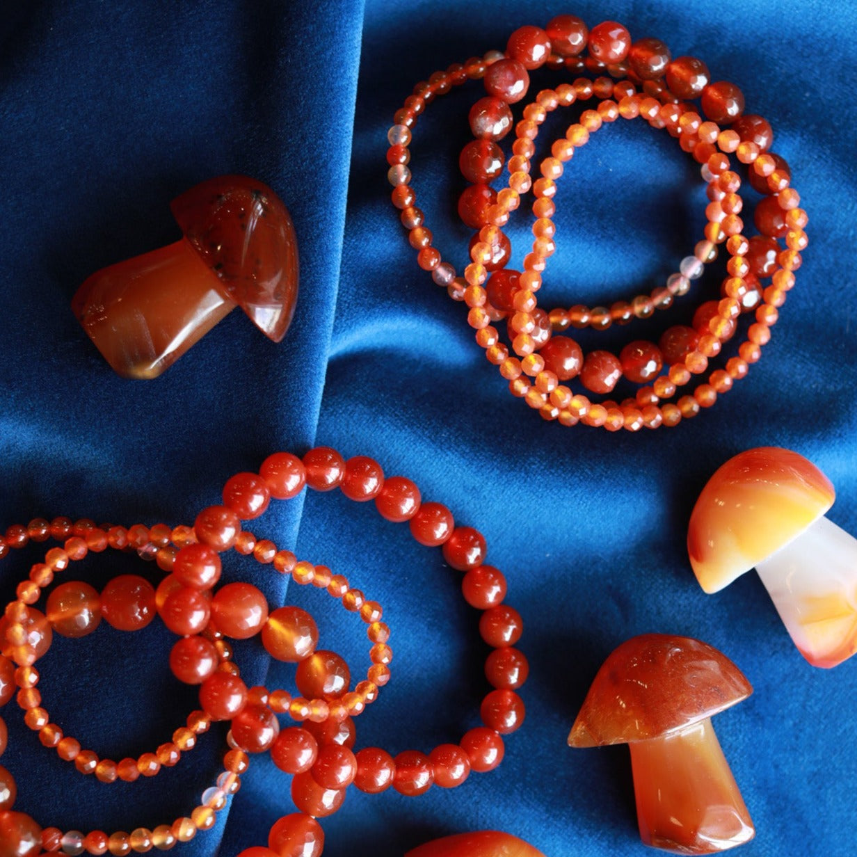 Carnelian Bracelet Assortment on Blue Velvet with Scattered Carnelian Mushrooms