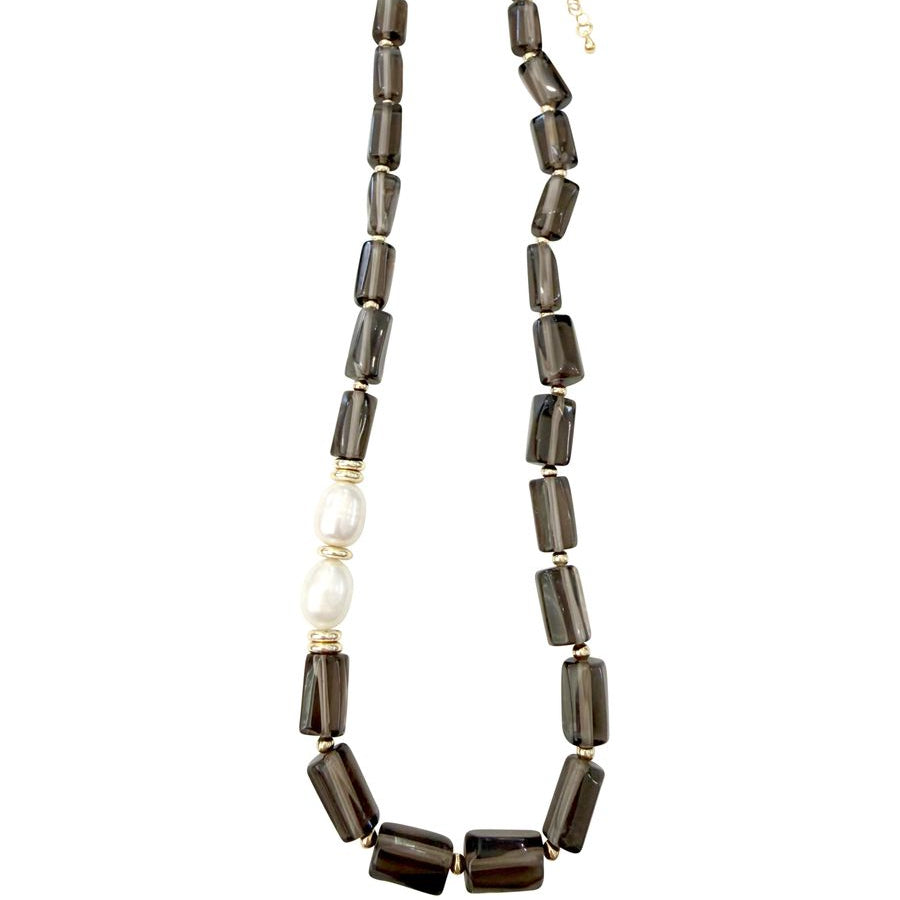 A beaded necklace featuring dark brown translucent rectangular smoky quartz beads, a single white pearl bead, and small gold spacer rings, displayed on a clean white background.