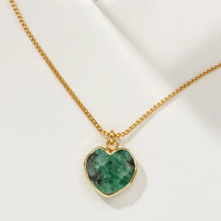 Gold necklace with a green heart-shaped pendant on a white background