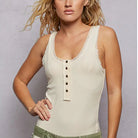 Woman wearing a cream tank top and green floral skirt against a gray background