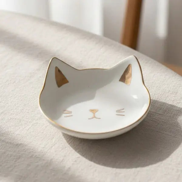 Cat-shaped ceramic dish with gold accents on a light surface