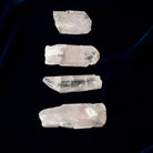 Four crystal Danburite stones arranged vertically on a dark background