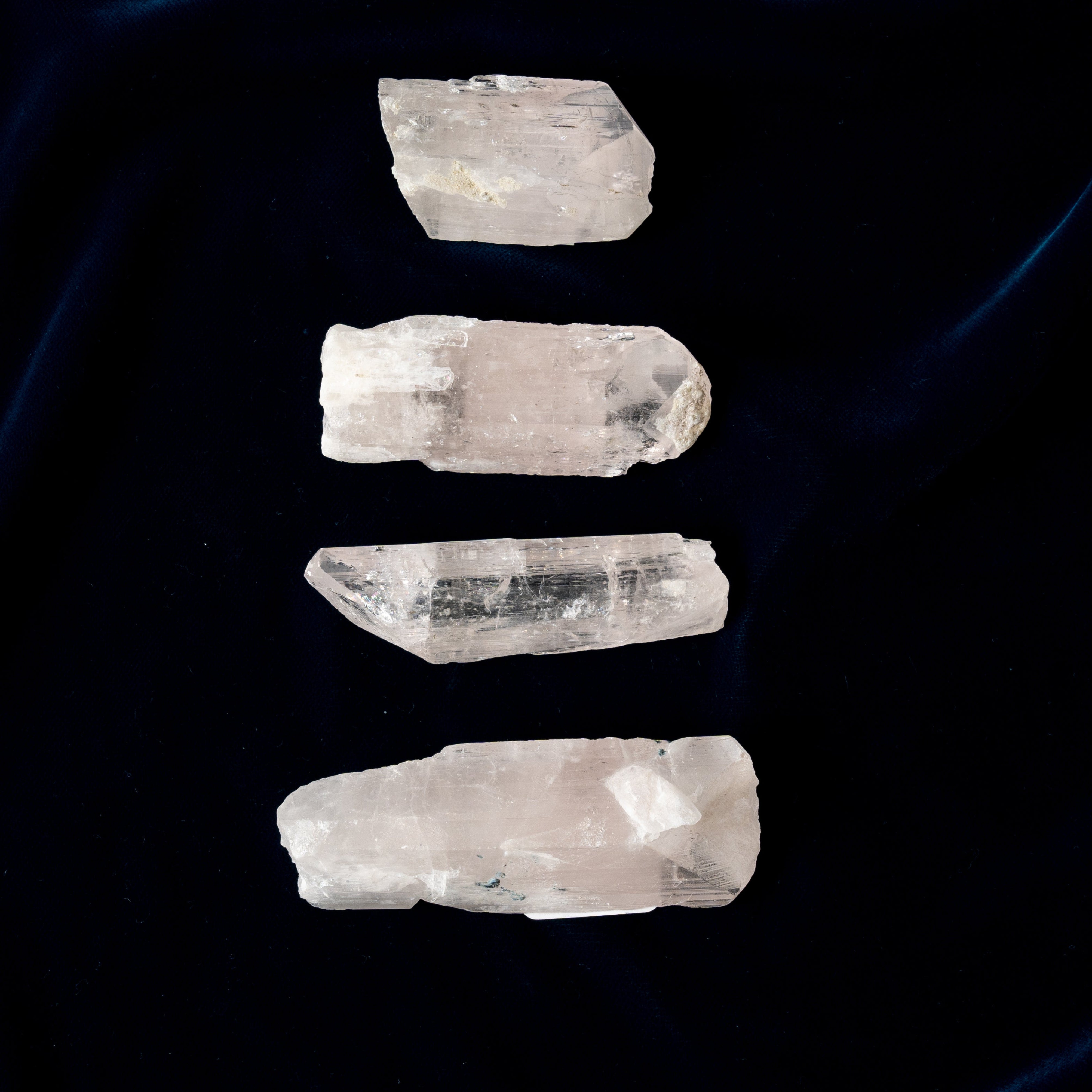 Four crystal Danburite stones arranged vertically on a dark background