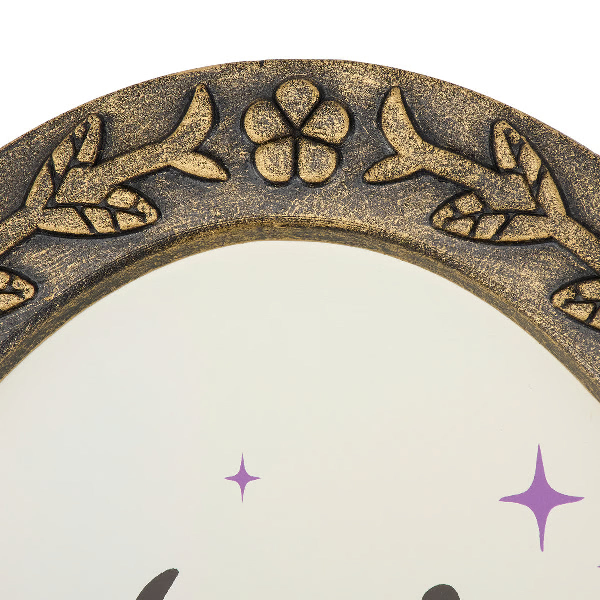 Close-up of an ornate round mirror frame with a distressed antique gold finish, featuring embossed floral and leaf motifs along the top curve, set against a plain white background.