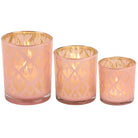 Set of three pink candle holders with gold geometric patterns on a white background