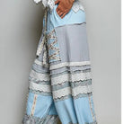 Light blue and gray patchwork harem pants with lace details, worn by a model in beige flip-flops against a neutral gray background.