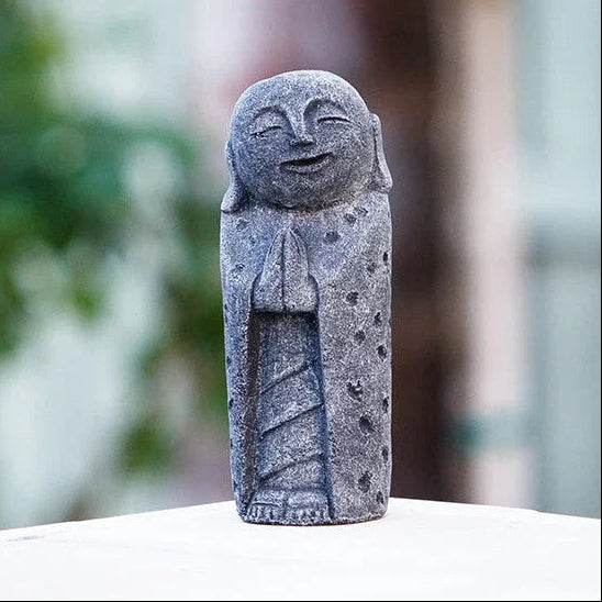 Stone statue of a smiling figure with a blurred natural background