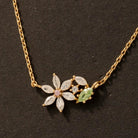 Gold necklace with floral and leaf designs on a dark background
