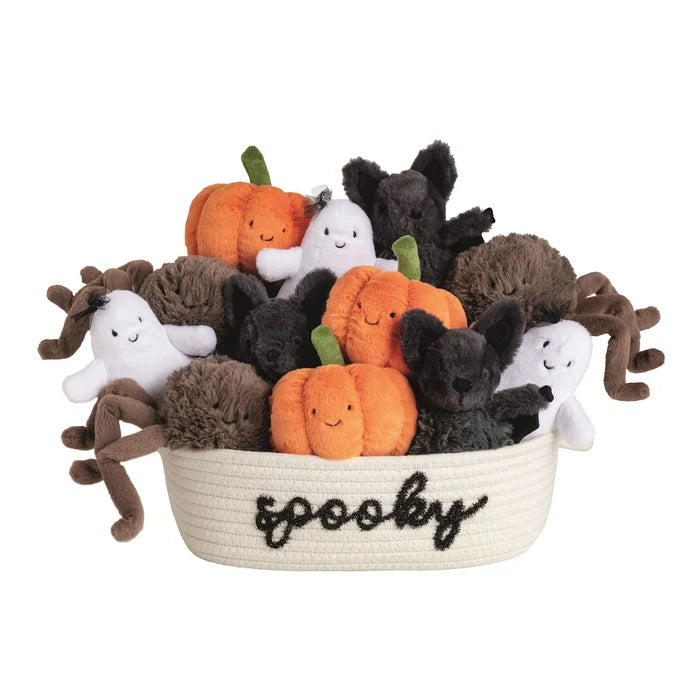 A collection of plush Halloween toys arranged in a cream woven basket with the word 'spooky' embroidered in black script. The set includes orange and green pumpkin characters, white ghosts, black cats, and brown spiders, all photographed on a clean white background.