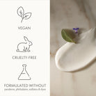 Product packaging with vegan, cruelty-free, and sulfate-free symbols on a marble surface.