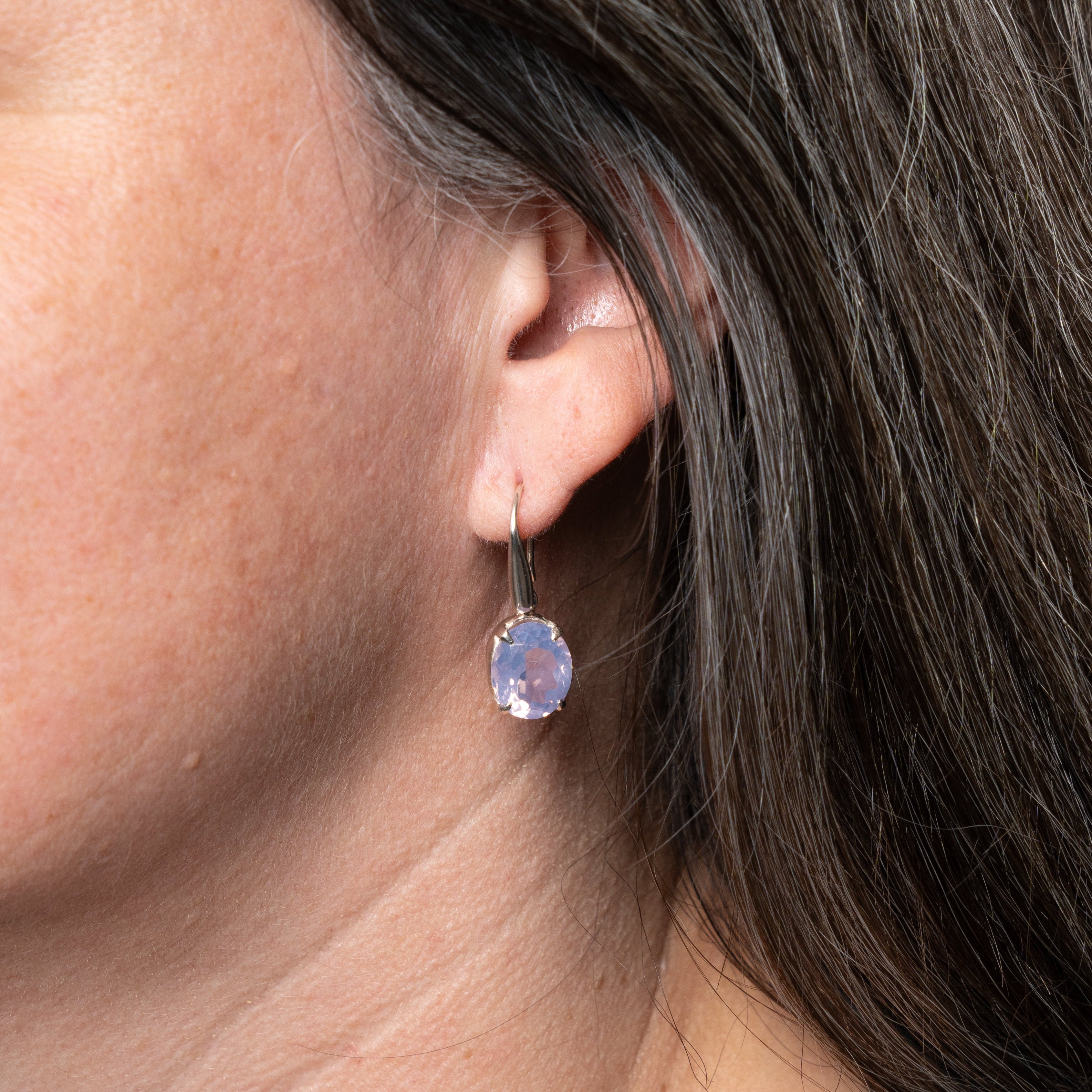 Close-up of an ear wearing a purple Lavender Quartz gemstone earring with dark hair 