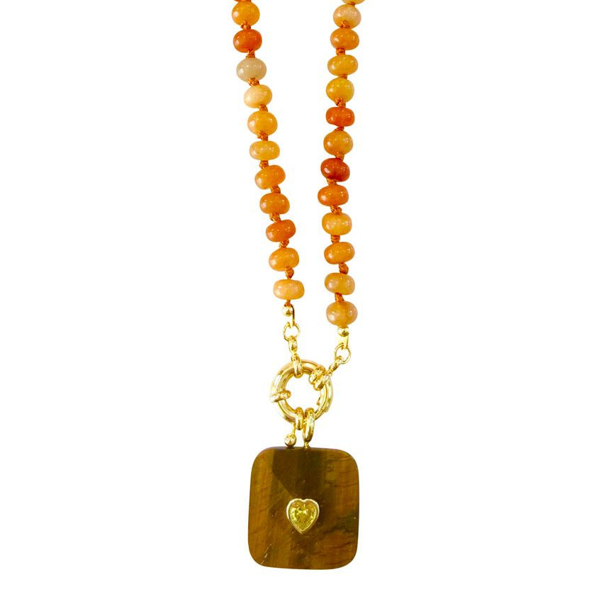 A beaded necklace featuring round orange and yellow red aventurine beads on a gold-tone chain, with a rectangular brown tiger's eye pendant and a small gold heart detail, shown against a plain white background.