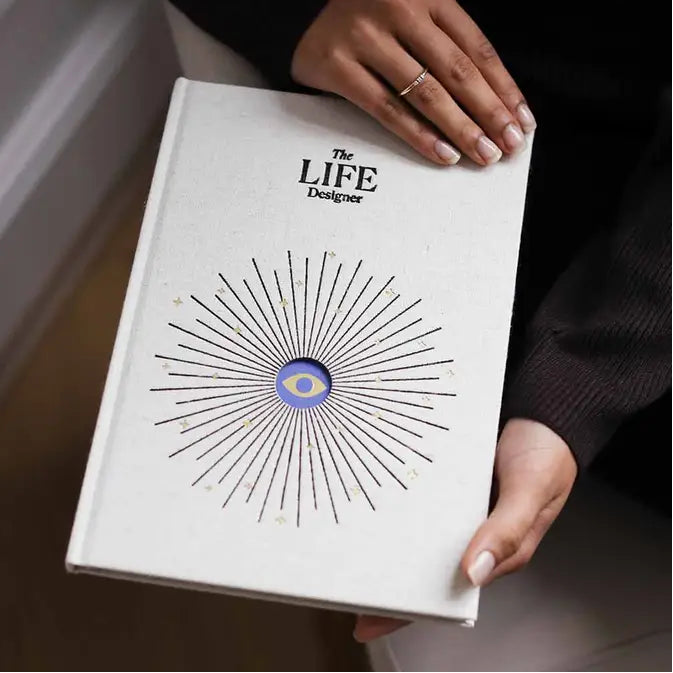 Book titled 'The Life Designer' held by a person with a decorative cover.