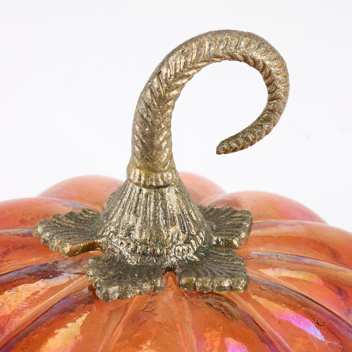 Close-up of a decorative pumpkin with a metallic gold twisted stem and a glossy orange surface with subtle iridescent highlights, set against a plain white background.